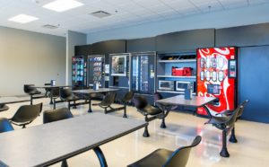 A shared dining area with tables, seating, and vending machines at HP Pelzer.