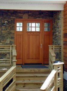 An exterior view of the front door of the woodsy homestead.