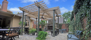 The backyard of the home after the addition of a covered bar area, outdoor seating area, outdoor fireplace, and a reconfigured landscape.